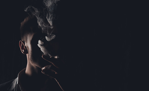 The silhouette of a person's face while smoking in the dark