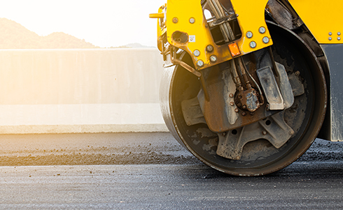 A steam roller flattening pavement
