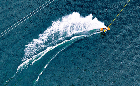 Image of a wakeboard being towed in ocean water with a large splash following