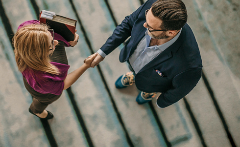 Two business-people shaking hands on steps
