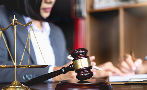 Two people reviewing a document in front of scales of Justice and a gavel