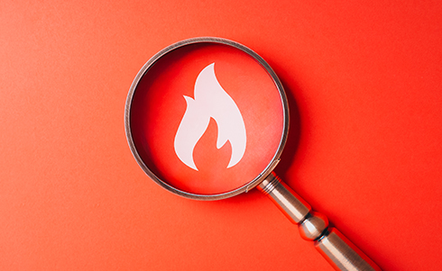 Magnifying glass over a fire logo
