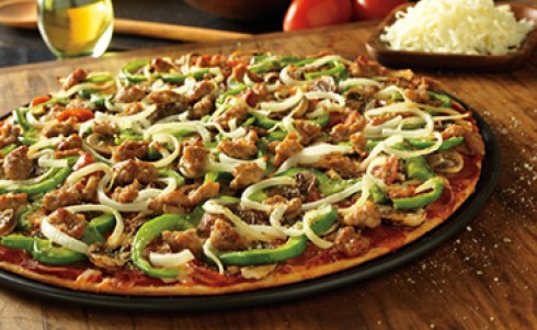 A Donatos pizza with green peppers, onion, and sauage with a plate of shredded cheese and a glass of wine next to it