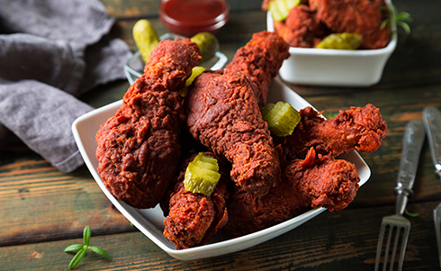 Lots of fried chicken on a plate with sliced pickles
