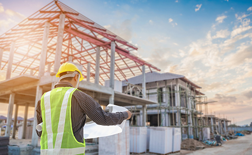 A construction worker reviewing plans outside at a construction site on a sunny day