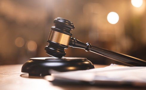 Judge gavel on the table with blurry books in the background