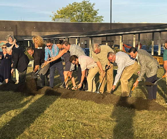 A group of folks conducting a ceremonial ground breaking with shovels