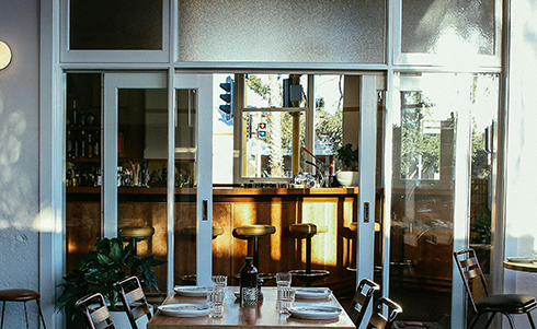 Image of a restaurant patio with the sun shining through two sliding glass doors