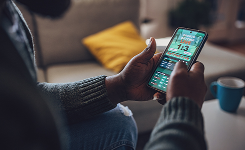 A person placing sports bets on his cell phone